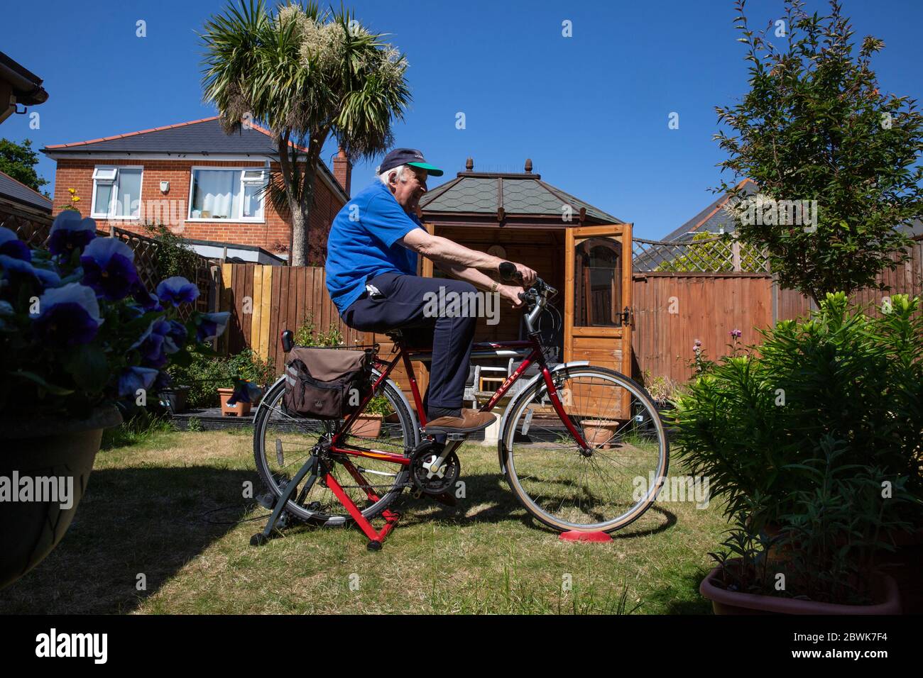 Les deux couples âgés dans leurs années 80 restant en forme sur un pied d'entraîneur de vélo dans leur jardin arrière pendant le verrouillage du coronavirus, sud-ouest de l'Angleterre, Royaume-Uni Banque D'Images
