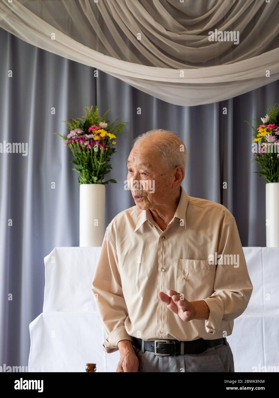 Un homme asiatique âgé prononce un discours lors d'un événement familial Banque D'Images