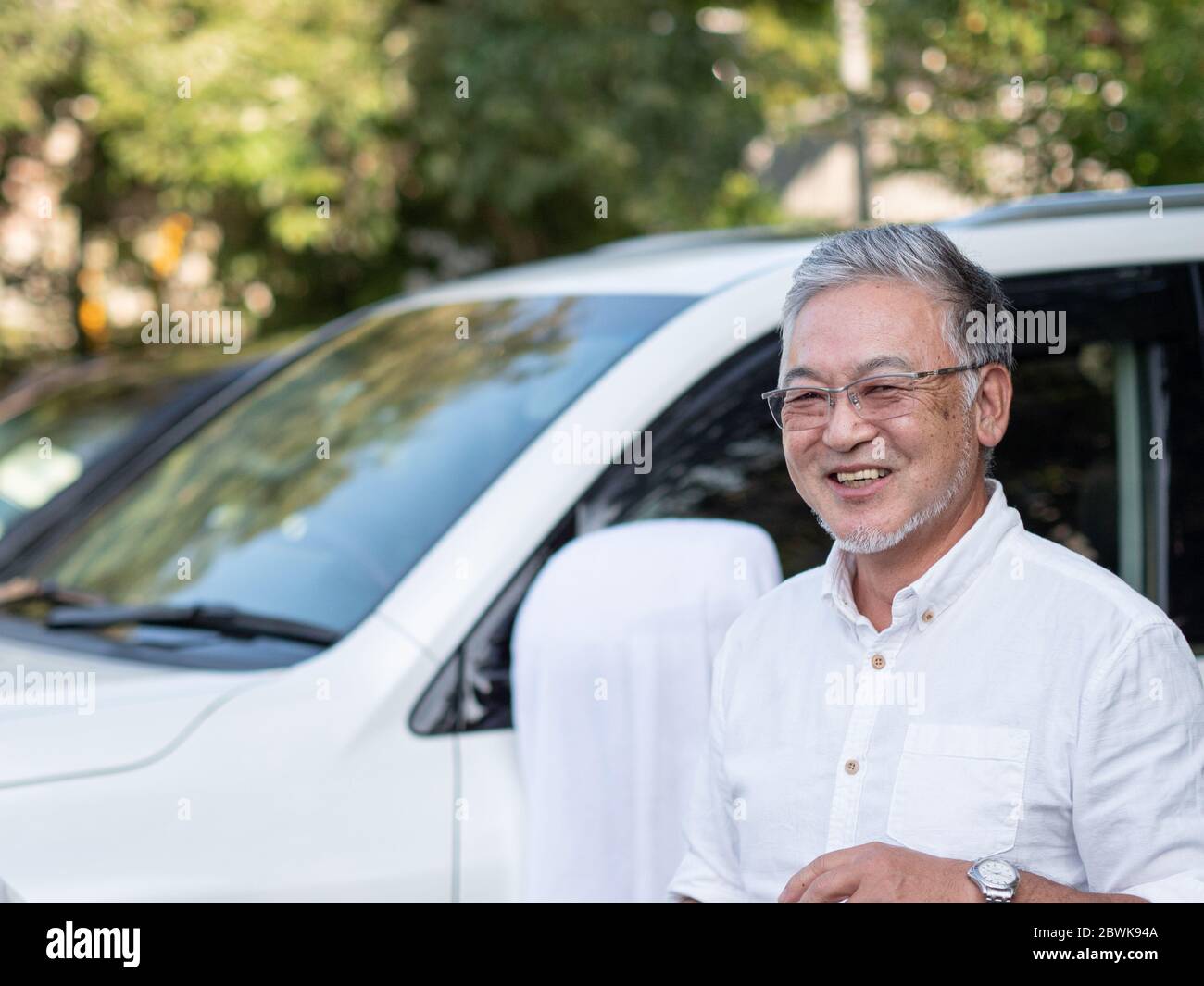 Un homme plus âgé se tenait devant sa voiture, à l'allure élégante. Banque D'Images