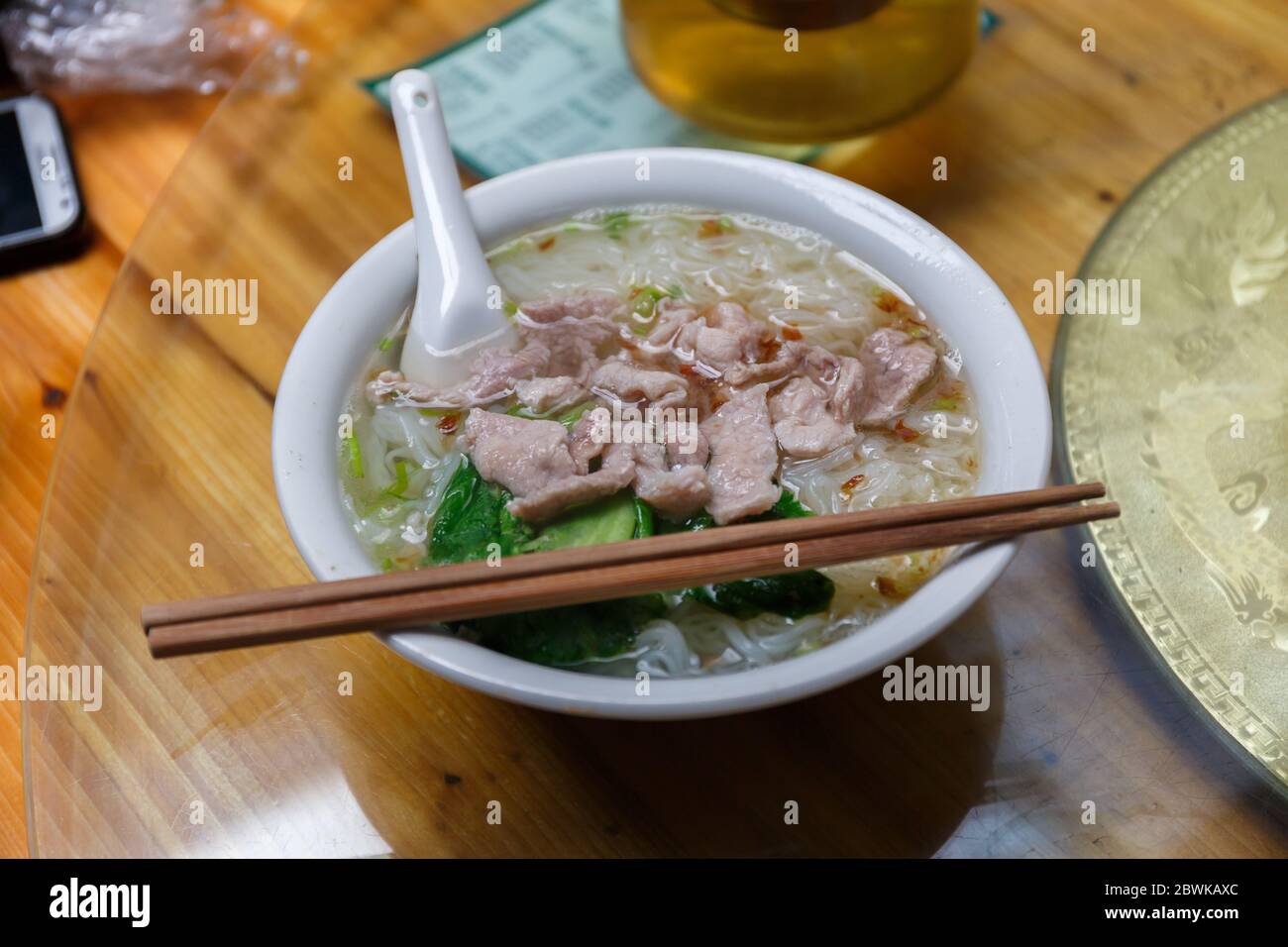 Bol avec nouilles de porc. Un plat chinois traditionnel. Prêt à manger avec des baguettes et une cuillère. Banque D'Images