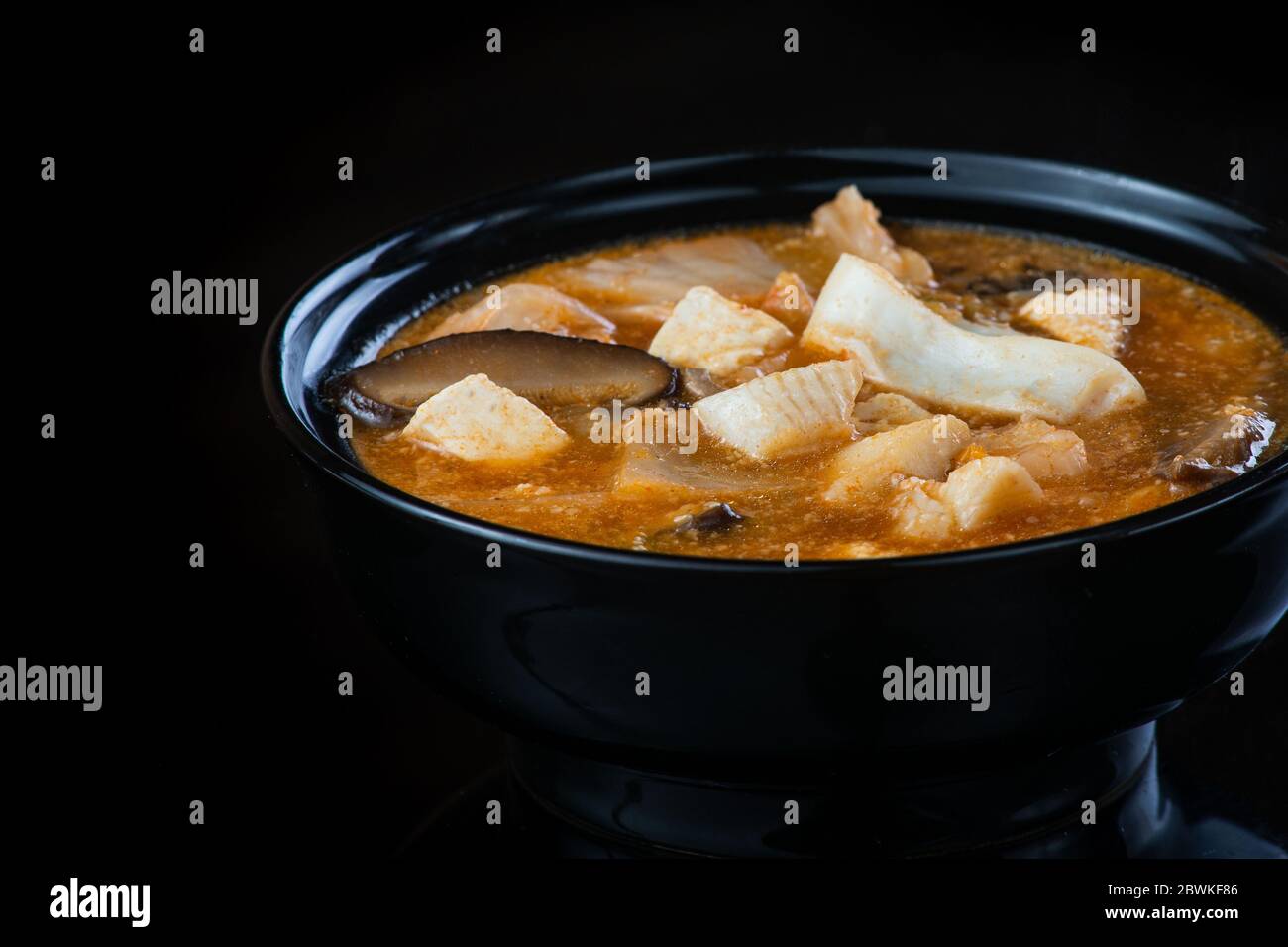 Soupe japonaise au poulet, œuf, champignons Simeji et aubergine sur fond sombre dans une assiette noire. Gros plan Banque D'Images