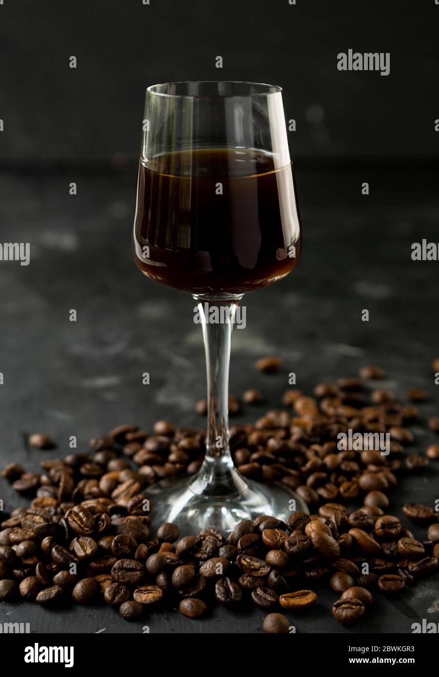 liqueur de café sombre et intense avec grains de café rôtis. dans une pile haute sur fond noir Banque D'Images