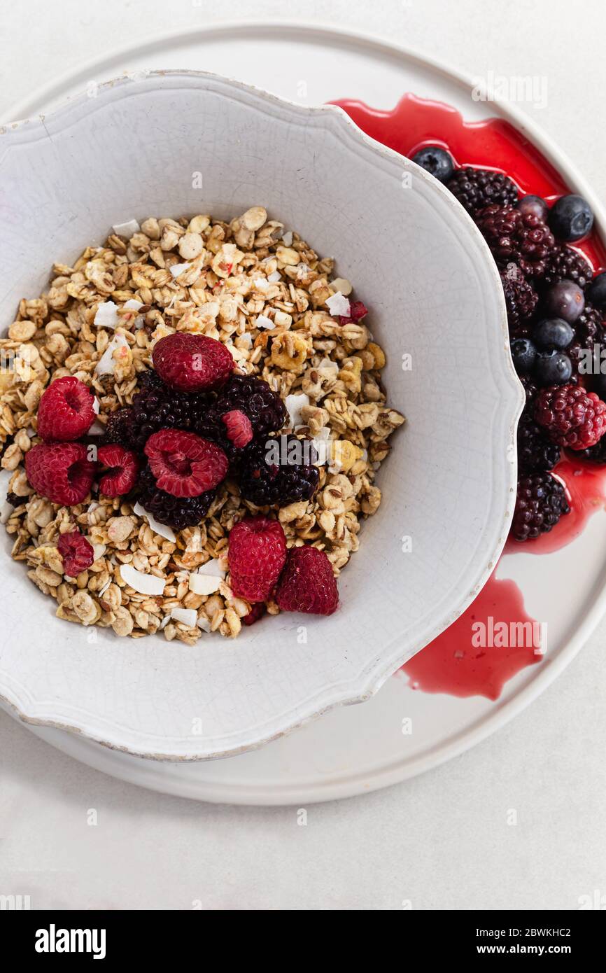 Image minimaliste de la granola avec baies dans un bol rustique blanc. Banque D'Images