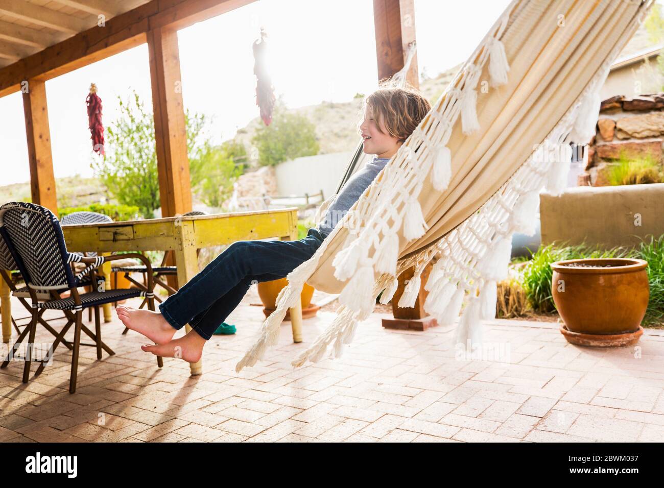 Garçon de six ans balançant dans un hamac sur une terrasse. Banque D'Images