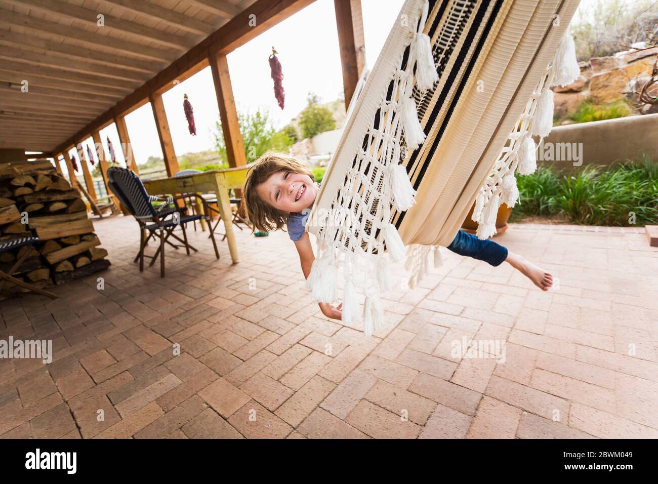 Un garçon de six ans balançant sur un hamac sous le patio Banque D'Images