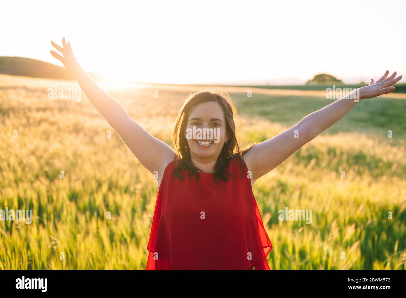 Les jeunes femmes sont soulevées jusqu'au ciel, célébrant la liberté. Émotions positives sentir la vie perception succès, paix de l'esprit concept. Fille heureuse gratuite dans un pré d'été profitant du coucher de soleil dans la nature . Banque D'Images