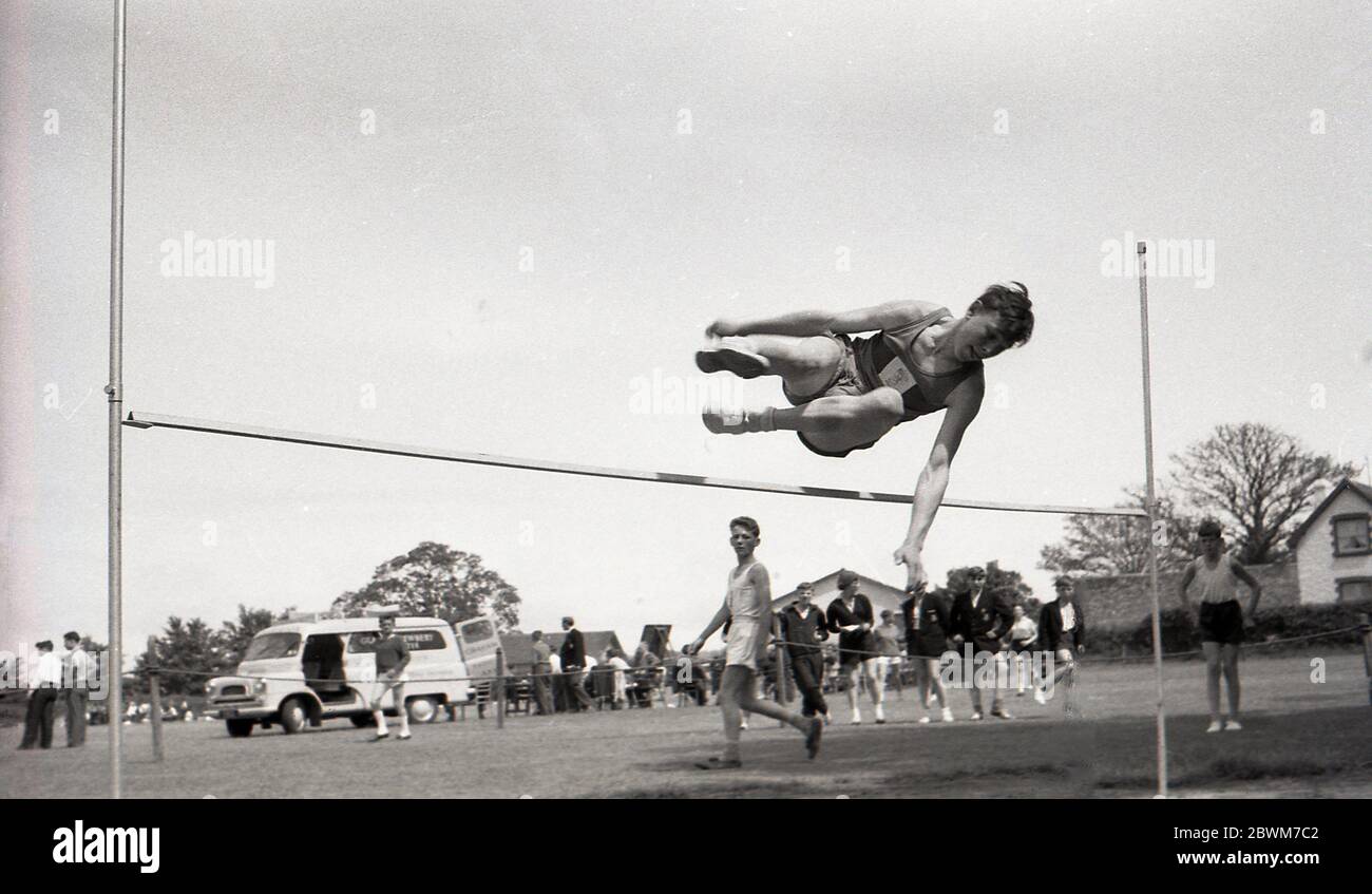 Années 1950, historique, été et un jour de sport scolaire, un adolescent sautant sur la barrière dans la compétition de saut élevé, Angleterre, Royaume-Uni. Banque D'Images
