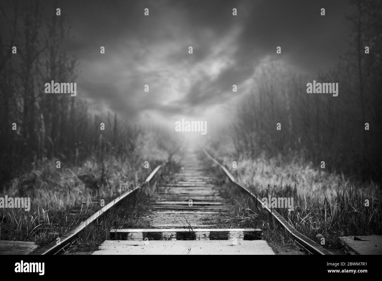 Perspective de chemin de fer vide et panneau de bordure en bois rayé sont sous ciel orageux dramatique, fond noir et blanc photo Banque D'Images