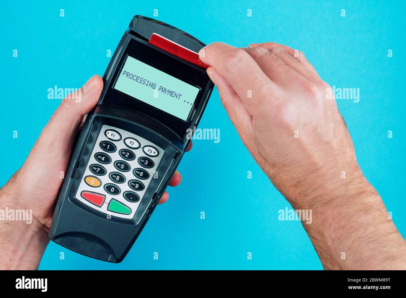 Vue de dessus de la personne passant par une carte de crédit ou de débit via le terminal de paiement du PDV Banque D'Images