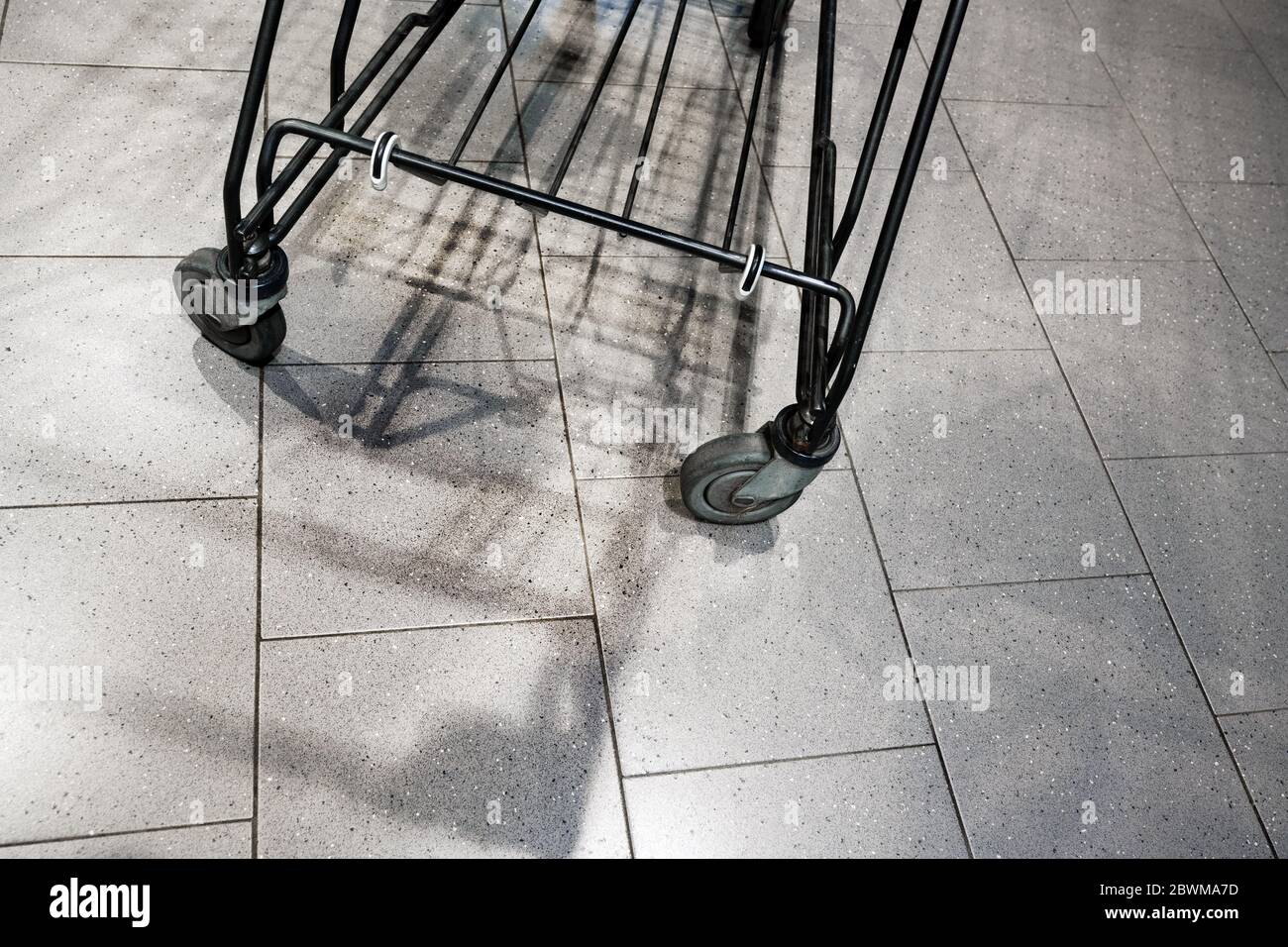 Roues et ombres d'un panier vide dans un supermarché allemand après l'achat de panique due à la propagation de covid-19, coronavirus, backgro abstrait Banque D'Images