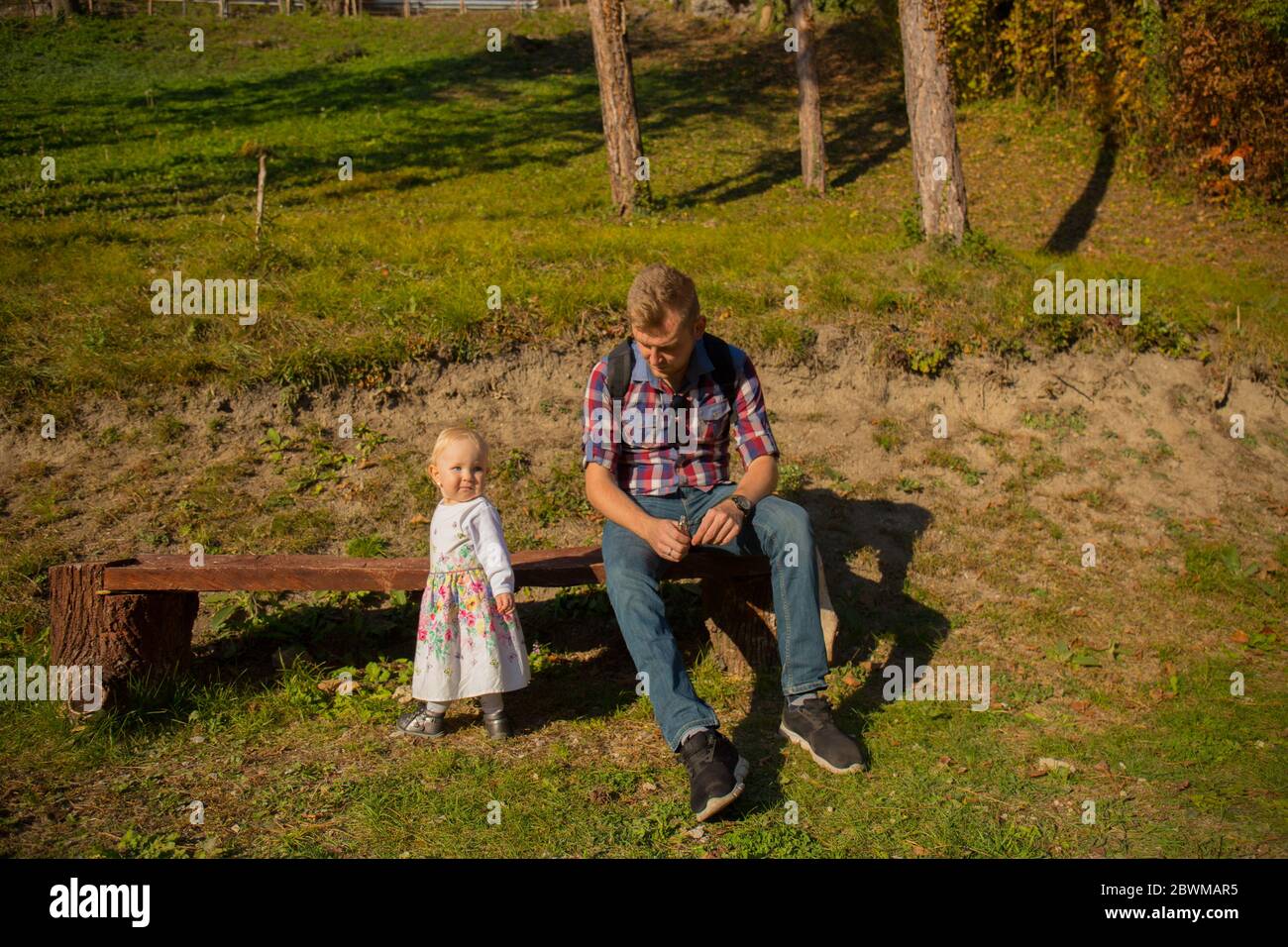 père et fille s'assoient sur un banc dans une belle nature, en forêt, dans un parc, jour ensoleillé, petite fille Banque D'Images