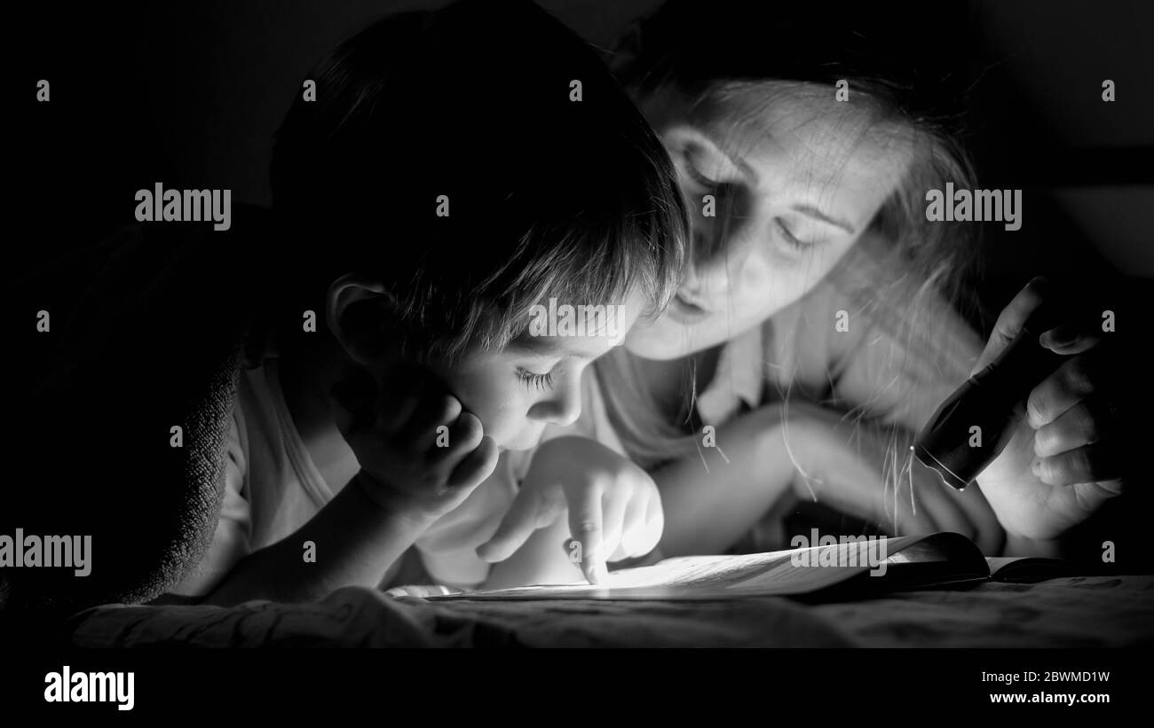 Portrait Noir Et Blanc Du Livre De Lecture De Petit Garcon Avec Mere Couche Sous Couverture La Nuit Photo Stock Alamy