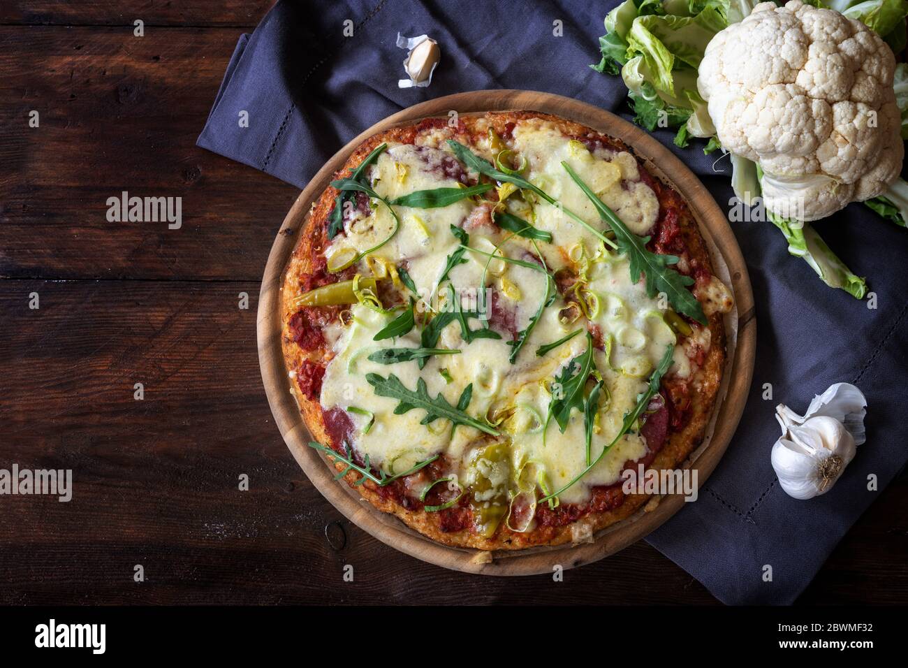 Pizza avec une croûte de chou-fleur déchiqueté sur une table en bois rustique sombre, alternative pour le carb bas ou régime cétogène, espace de copie, vue de dessus d'abov Banque D'Images