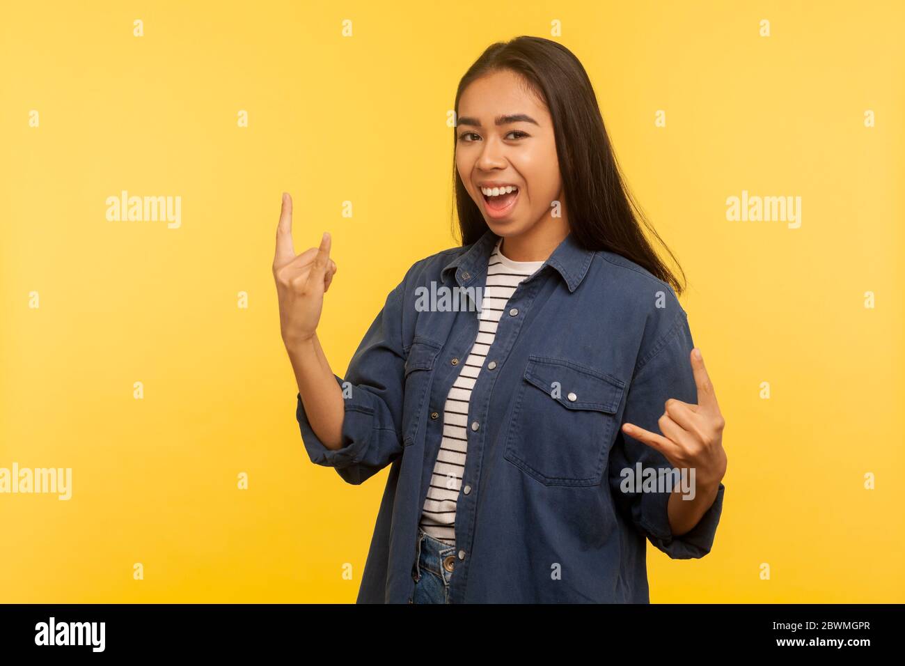 Oui, c'est merveilleux ! Portrait de fille joyeuse en chemise en denim se sentant fou, montrant des cornes de diable, rock et mouvement de la main de rouleau, ravi de la réussite Banque D'Images