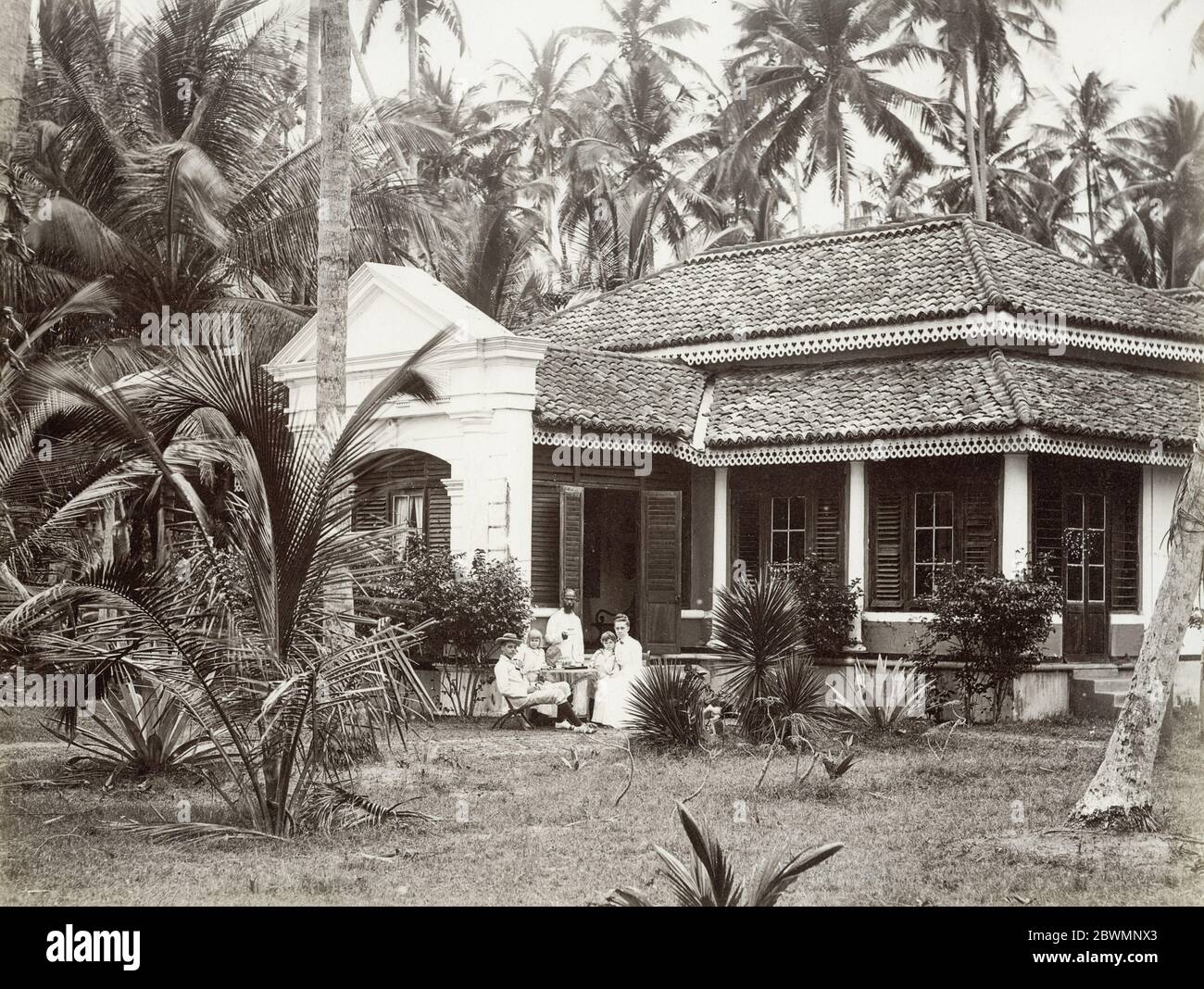 Photographie vintage du XIXe siècle - famille européenne à l'extérieur de leur bungalow colonial, avec un serviteur, Singapour ou le sud-est asiatique emplacement. Banque D'Images