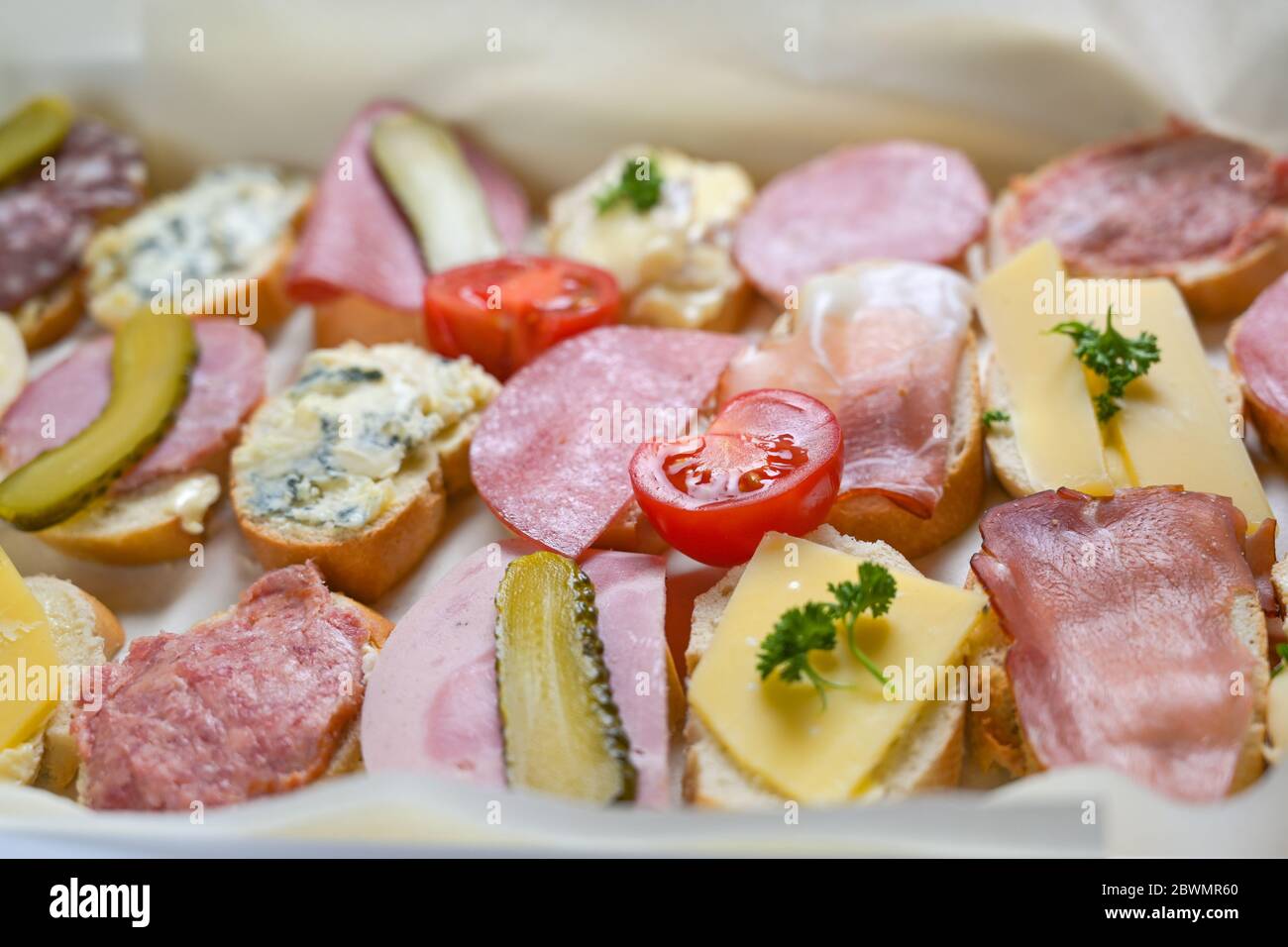 Plusieurs canapés de baguette au fromage et à la saucisse, tomates et cornichons servis sous forme de buffet décontracté, sélection de produits, champ étroit Banque D'Images