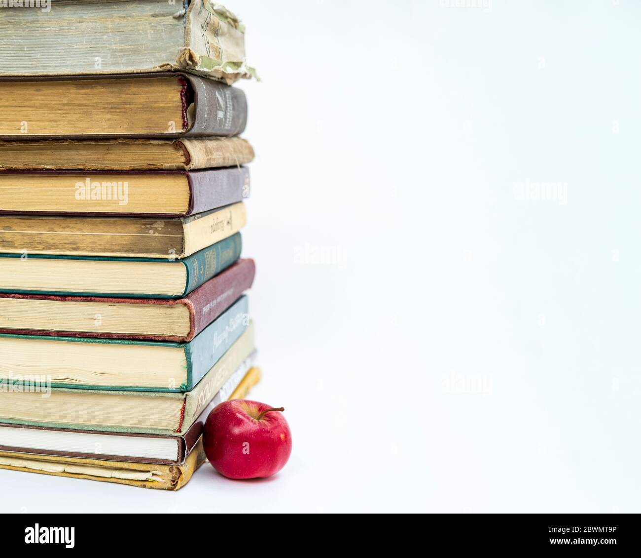 une pile de vieux livres. Une pomme rouge se trouve à proximité. Le concept d'une idée est venu comme une pomme de Newton. Sur fond blanc. Banque D'Images