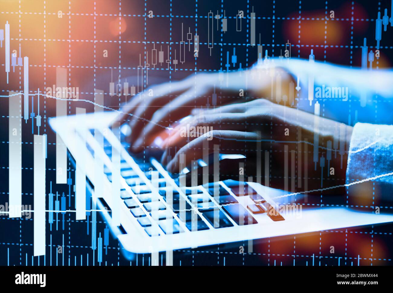 Mains sur un clavier d'ordinateur avec divers graphiques montrant les cours de la bourse Banque D'Images