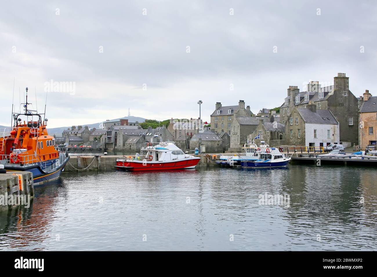Port avec bateaux de pêche, bateau de sauvetage et bâtiments en arrière-plan, Lerwick, Shetland Islands, Écosse. Banque D'Images