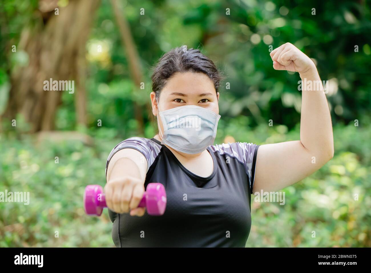 Les femmes saines et fortes font de l'exercice physique porter un masque de protection pour la protection contre les virus dans le parc vert public. Banque D'Images