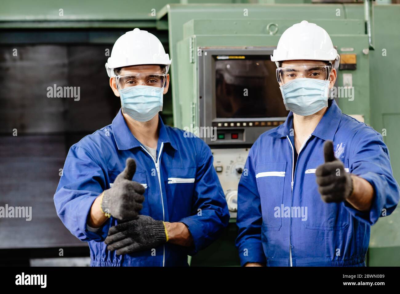 Un travailleur portant un écran facial ou un masque facial jetable pendant le travail en usine pour prévenir la pollution par le coronavirus (Covid-19) ou la poussière d'air en usine Banque D'Images