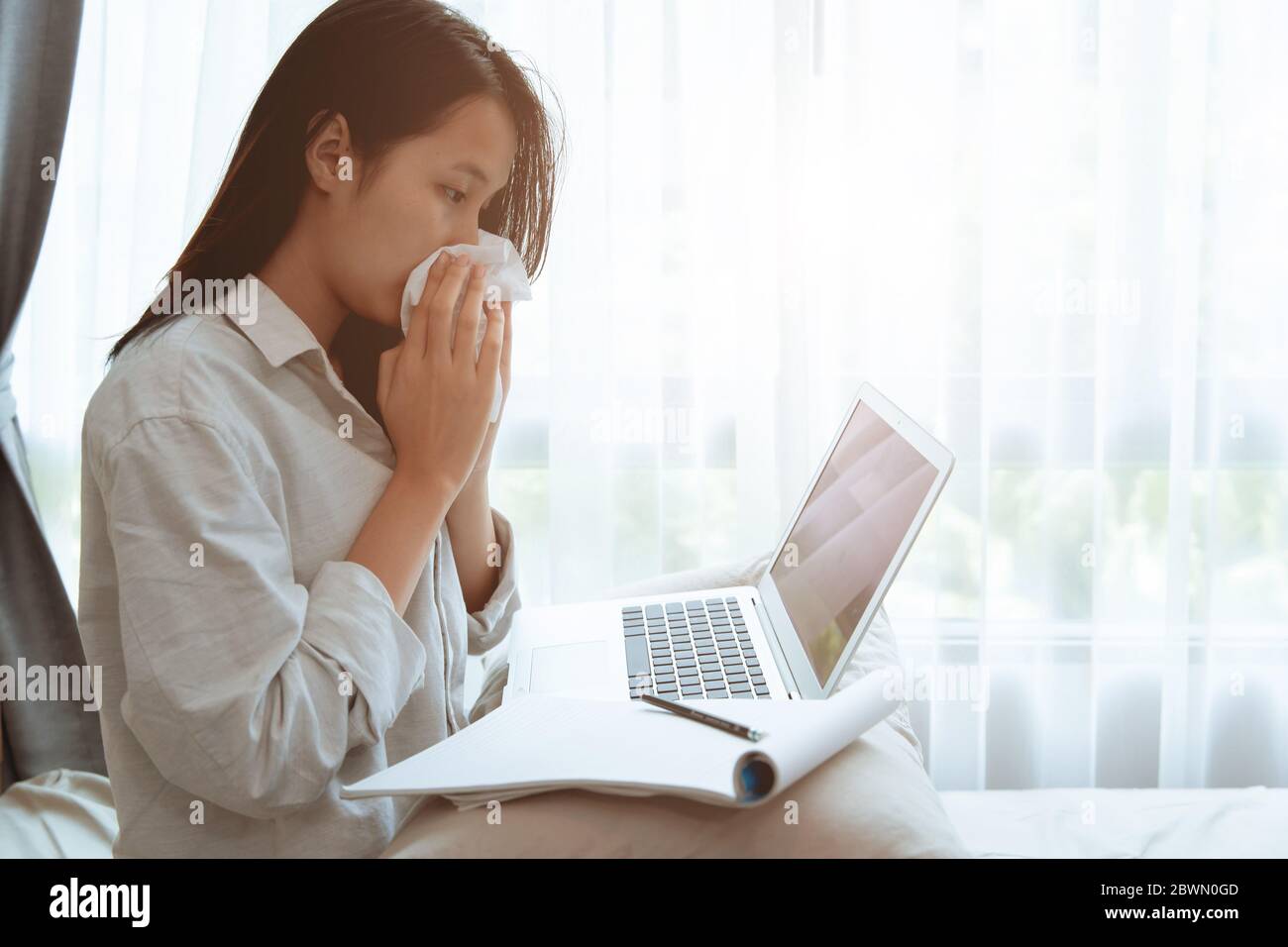 Jeune fille qui se fait essuyer le nez tout en ligne homeschooling avec la grippe maladie coronavirus(Covid-19) infecté, rester à la maison travaillant avec ordinateur portable autosoins dur Banque D'Images