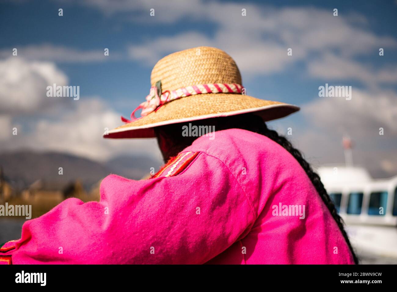 La femme de la communauté Uros sur le bateau traditionnel fait de totora roseaux avec des touristes, portant des vêtements traditionnels, et un chapeau. Banque D'Images