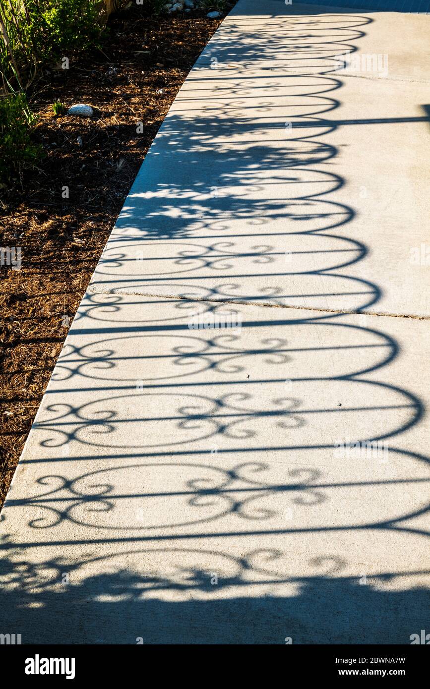 Une clôture en fer projette des ombres sur le trottoir; au cœur du jardin de guérison du centre médical régional des Rocheuses; Salida; Colorado; États-Unis Banque D'Images