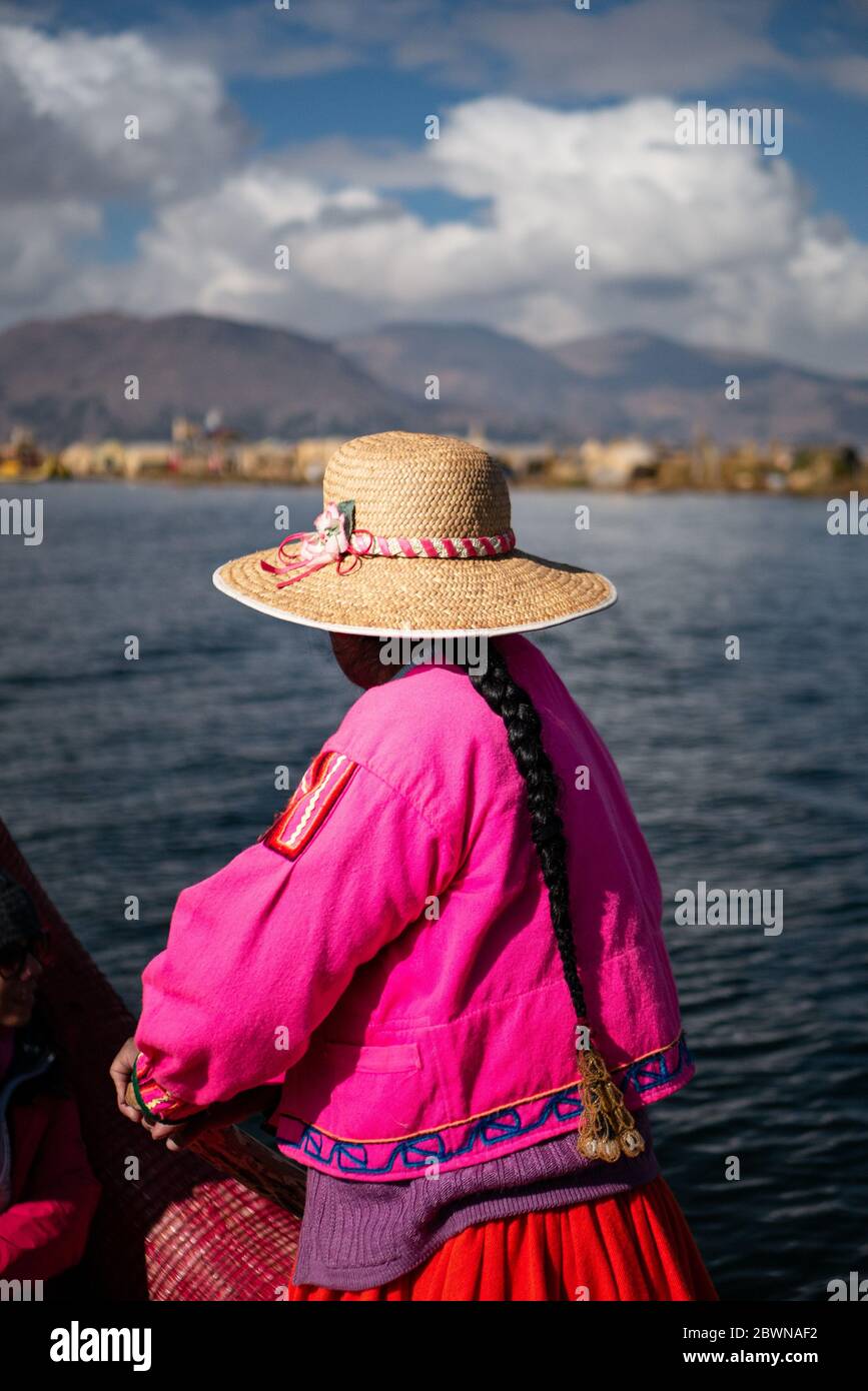 La femme de la communauté Uros sur le bateau traditionnel fait de totora roseaux avec des touristes, portant des vêtements traditionnels et un chapeau Banque D'Images