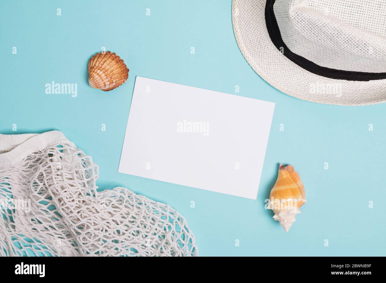 Accessoires d'été, coquillages et carte papier vierge sur fond bleu Banque D'Images