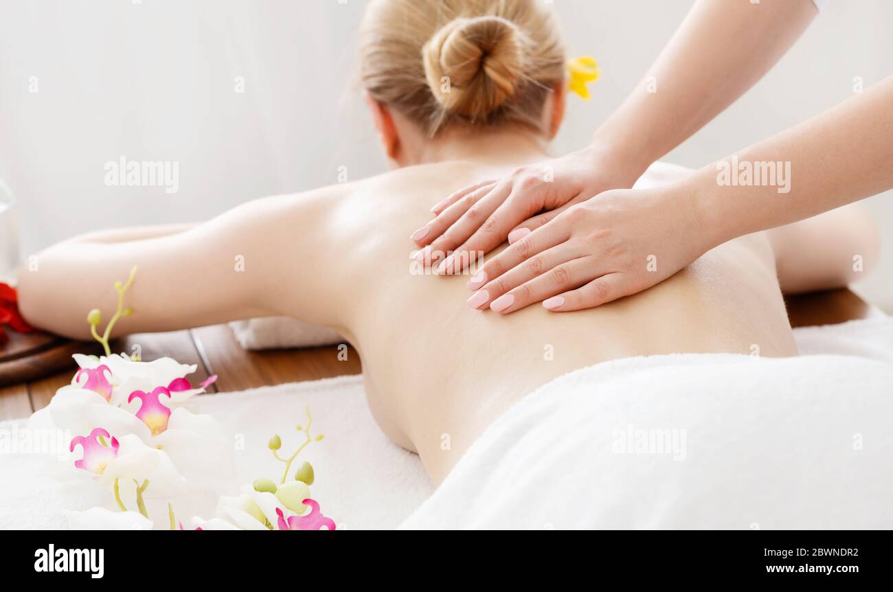 Détendez-vous et spa. Les mains de la femme sur le dos nu fille sur la  table de massage avec feuille blanche et orchidée Photo Stock - Alamy