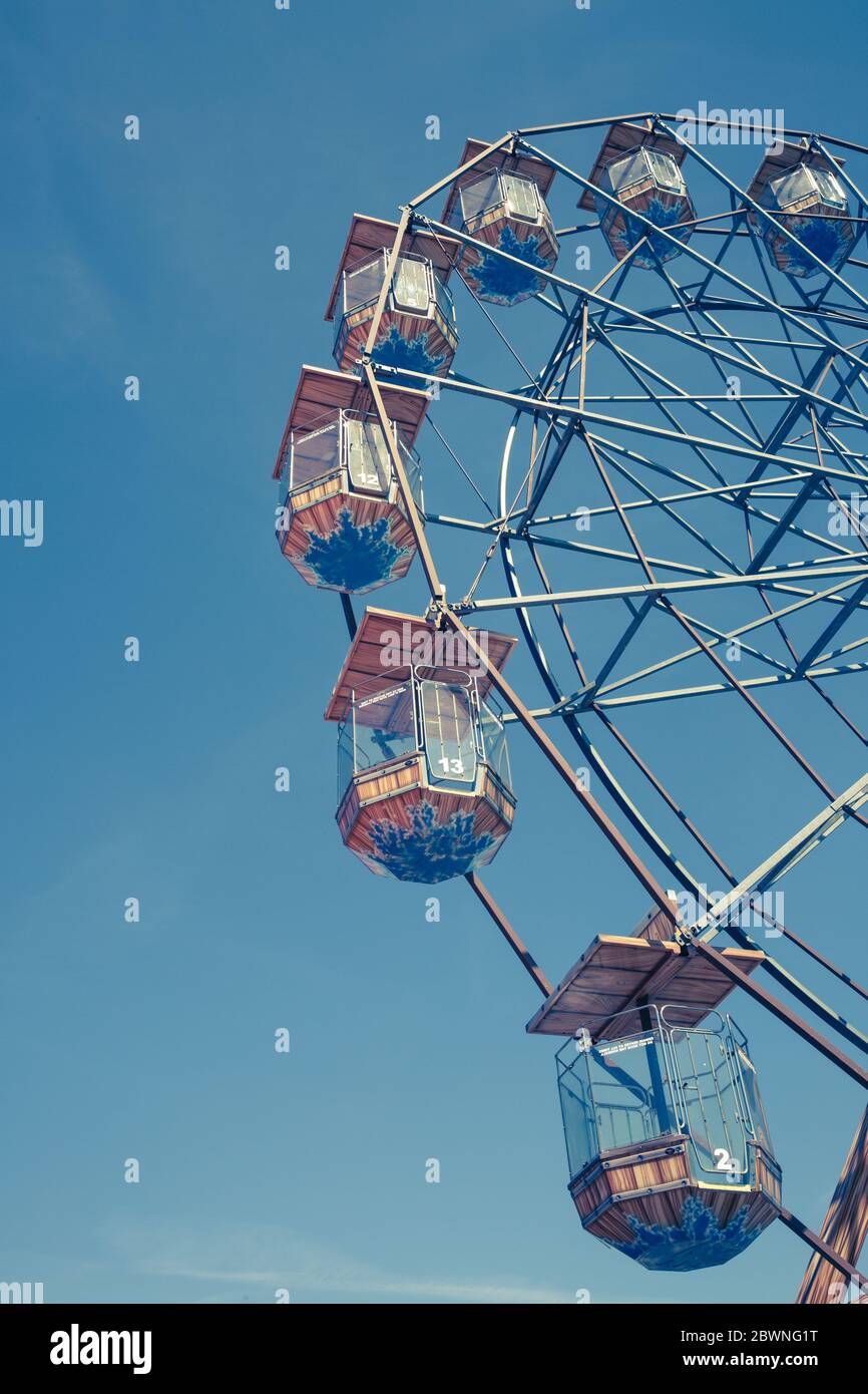 Vue en angle bas d'une excursion d'époque dans le parc des expositions Ferris Wheel avec sièges enfermé sous un ciel bleu et une composition verticale Banque D'Images