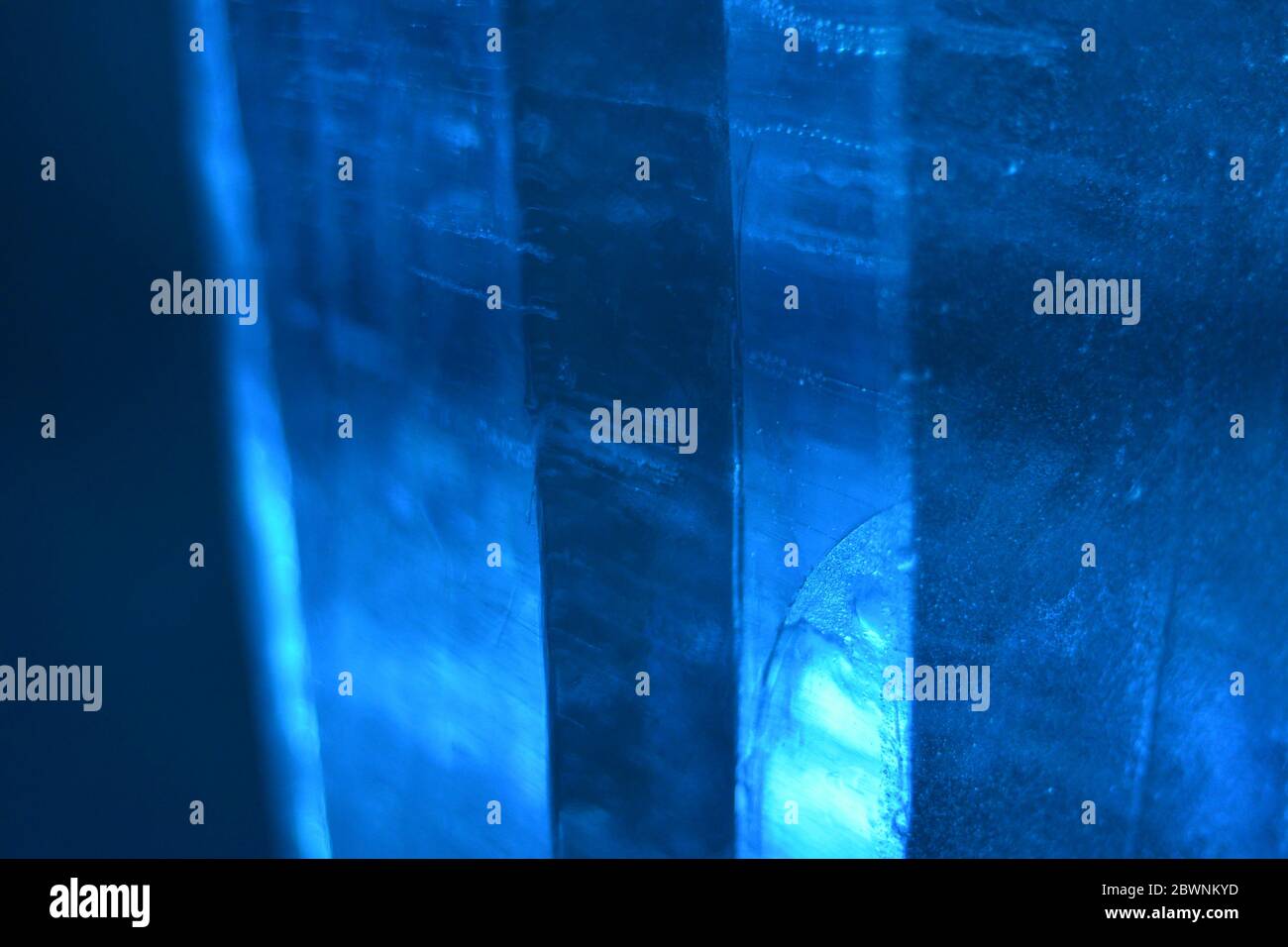 Des bulles sont piégées dans ces colonnes de glace bleue qui nagent et déforment la mise au point pour donner une photographie de texture d'arrière-plan monochromatique. Banque D'Images