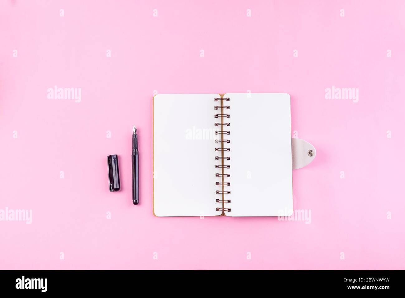 cahier d'école sur fond rose, bloc-notes en spirale sur une table, trombone de pose à plat ou objet pour le bureau appliquer concept Banque D'Images