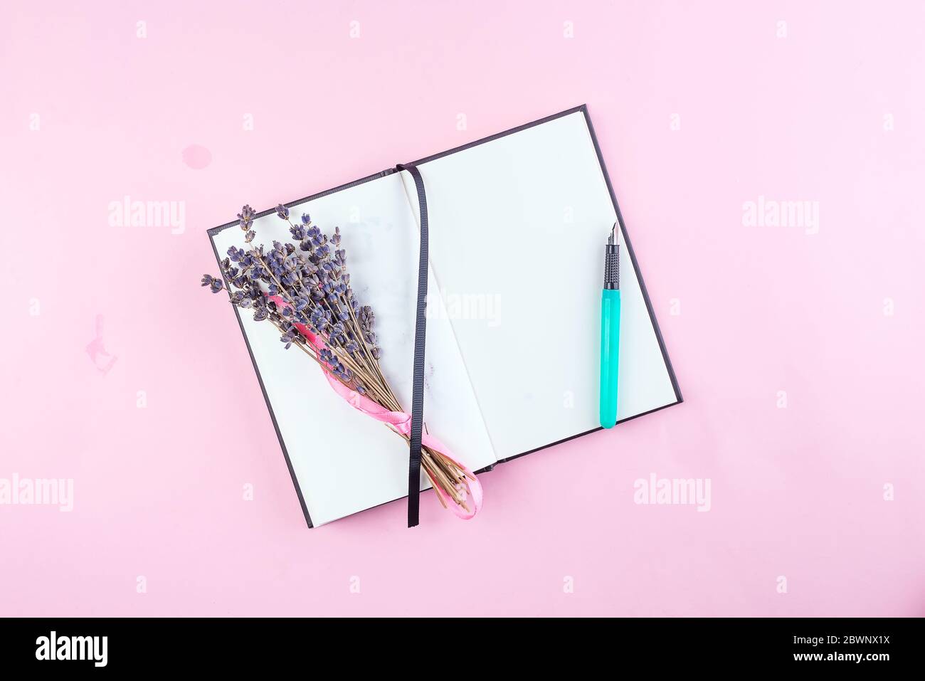cahier sur fond rose, bloc-notes en spirale sur une table, lavande séchée et stylo pour le bureau appliquer concept Banque D'Images