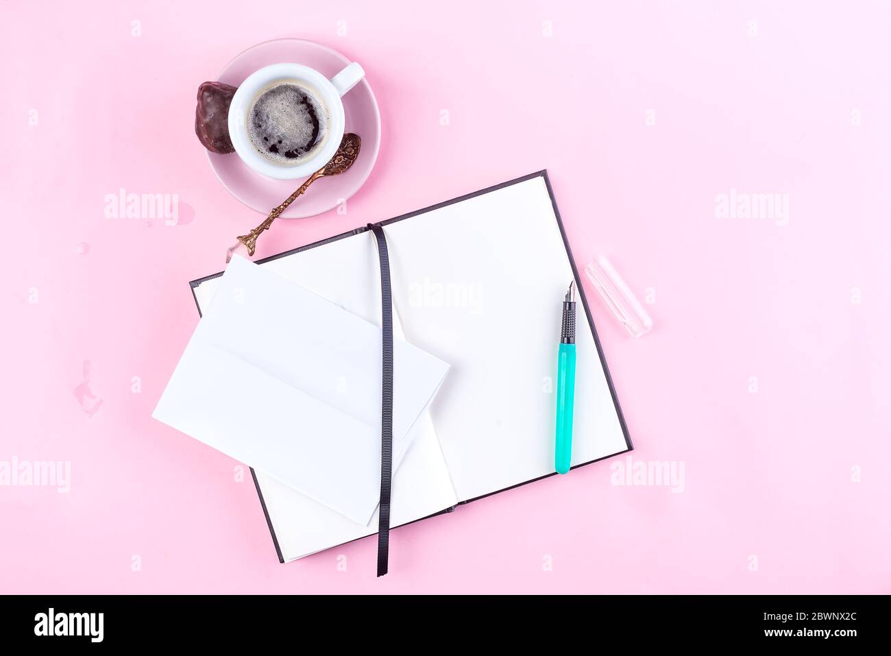 Tasse de café du matin pour le petit déjeuner, carnet vide, crayon et enveloppe sur table rose vue du dessus . Femme travaillant bureau. Banque D'Images
