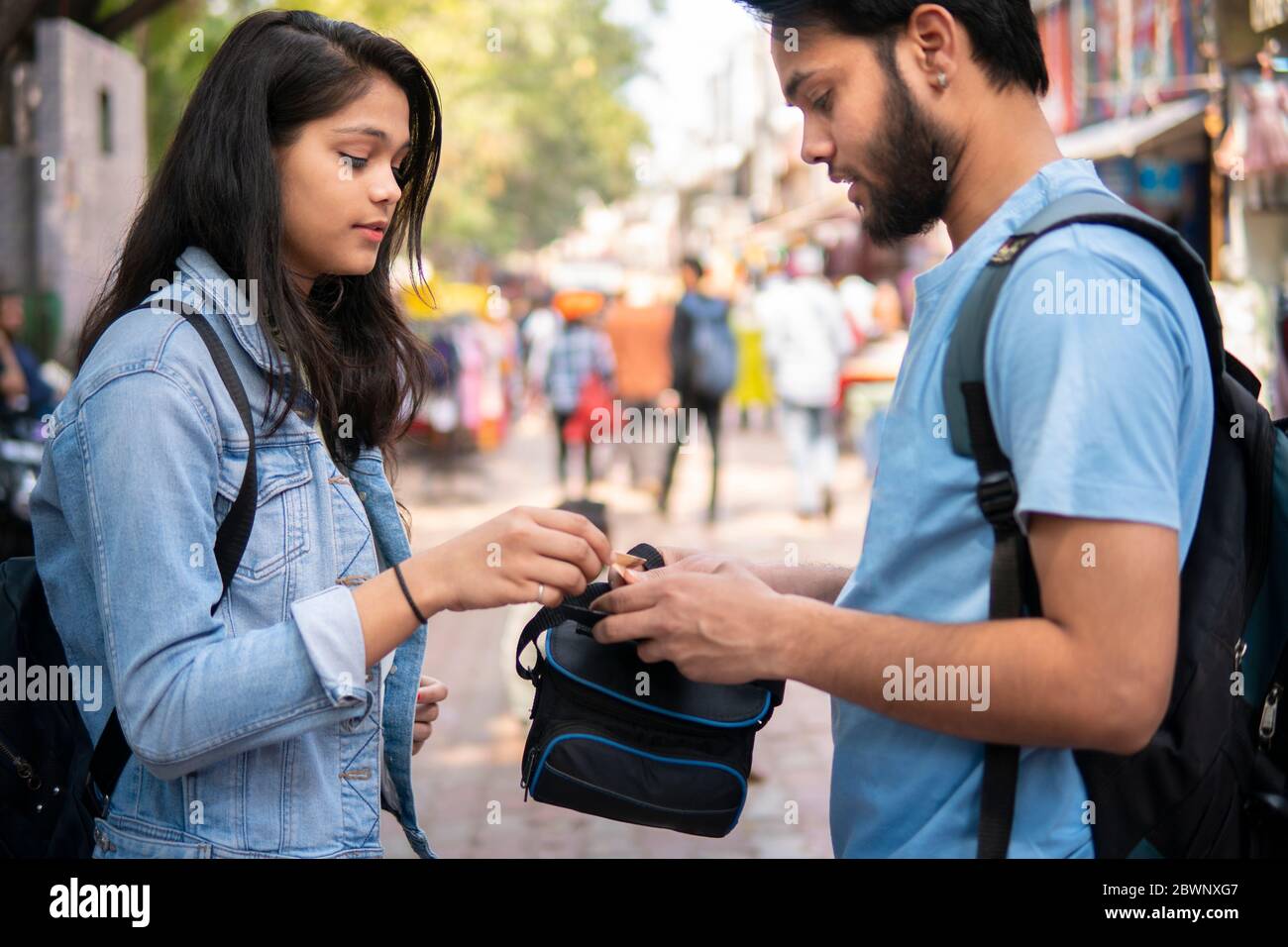 Frère aîné donnant de l'argent à sa sœur plus jeune pour faire du shopping dans le marché extérieur de rue en Inde. Banque D'Images