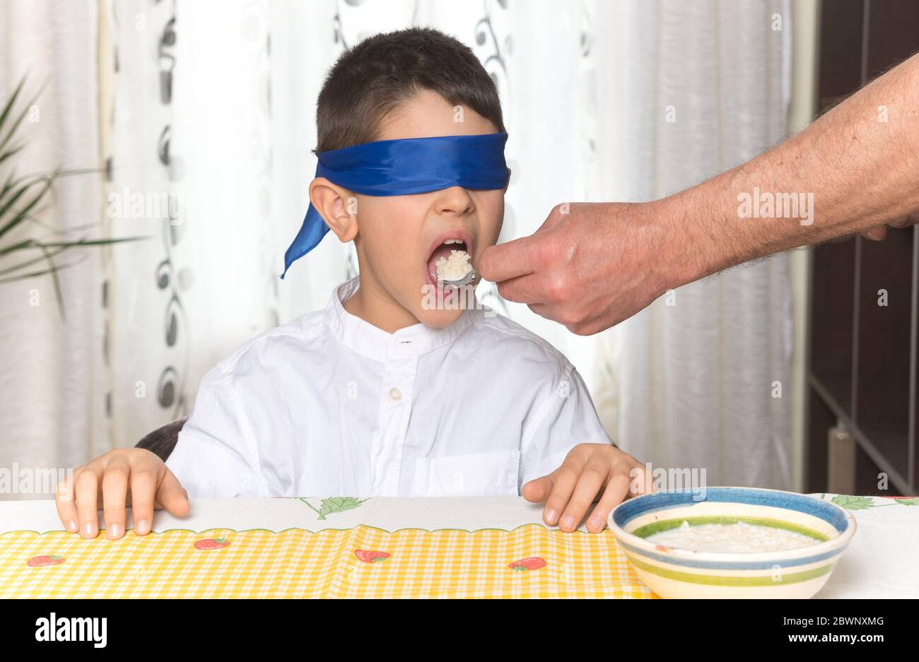 Test de goût, bandés garçon caucasien essayant une cuillère à soupe de riz. Banque D'Images