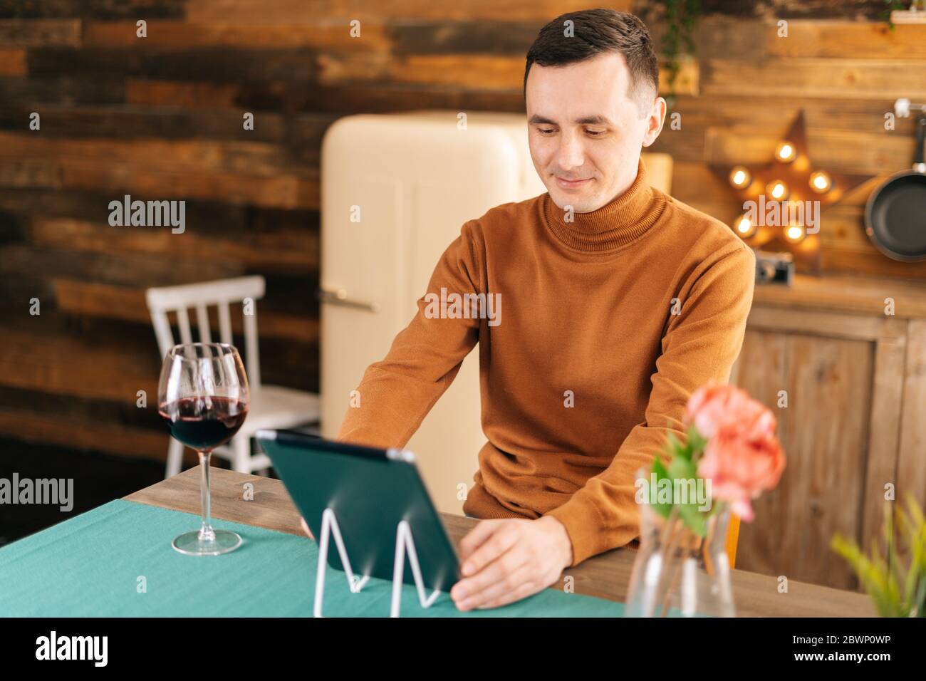 Jeune homme souriant utilisant une tablette informatique ayant chat vidéo en ligne avec des amis. Banque D'Images