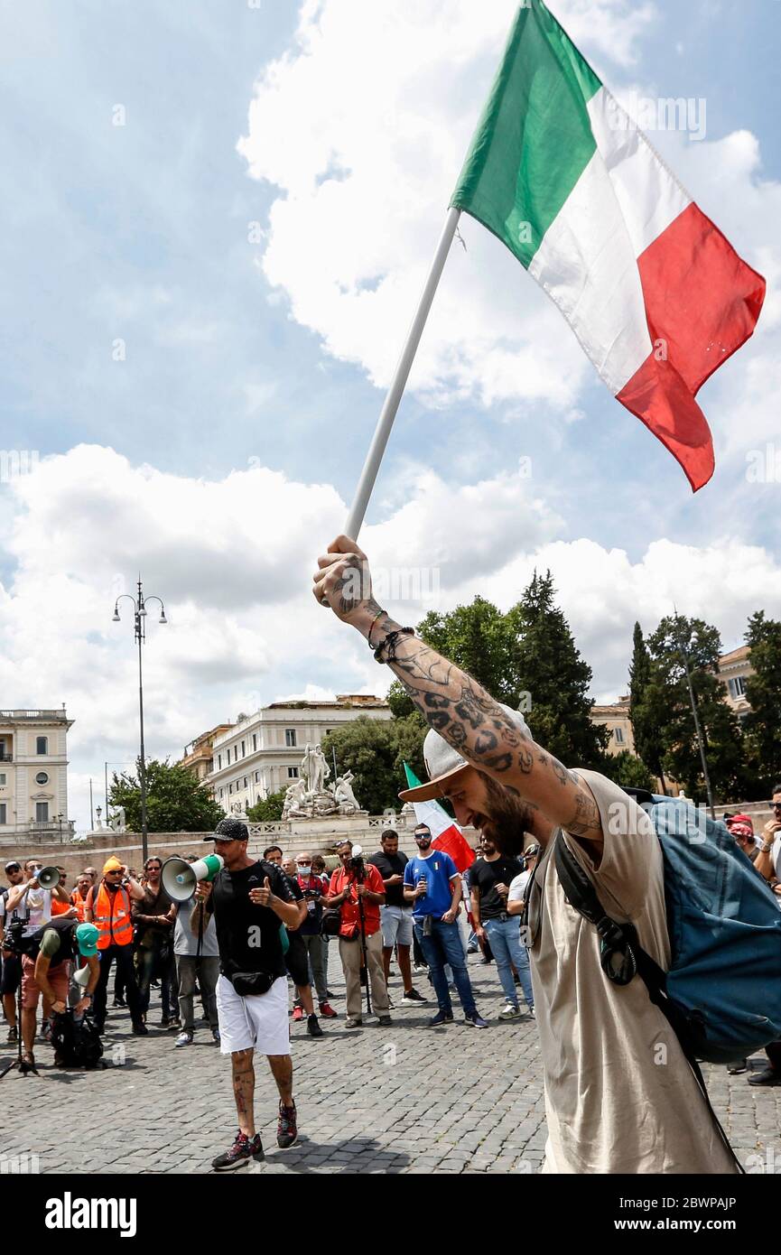 Rome, Italie. 02 juin 2020. Un manifestant parle alors qu'un autre marche portant un drapeau italien tricolore lors d'une manifestation à laquelle assistait le mouvement Orange Vêtes (Gilet Arancioni) lors d'une manifestation contre le gouvernement italien. Le mouvement Orange Vêtes rassemble plusieurs groupes de théoriciens du complot démenti du coronavirus, de sympathisants d'extrême droite et de gens ordinaires souffrant de l'impact économique du confinement imposé par le gouvernement pour enrayer la pandémie de Covid-19. Crédit: Riccardo de Luca - mise à jour des images/Alamy Live News Banque D'Images