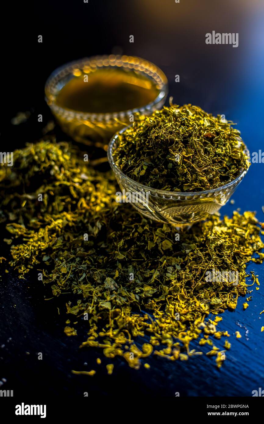 Prise de Kasuri methi cru et de sa pâte fraîchement préparée dans un bol en verre sur une surface noire brillante. Banque D'Images