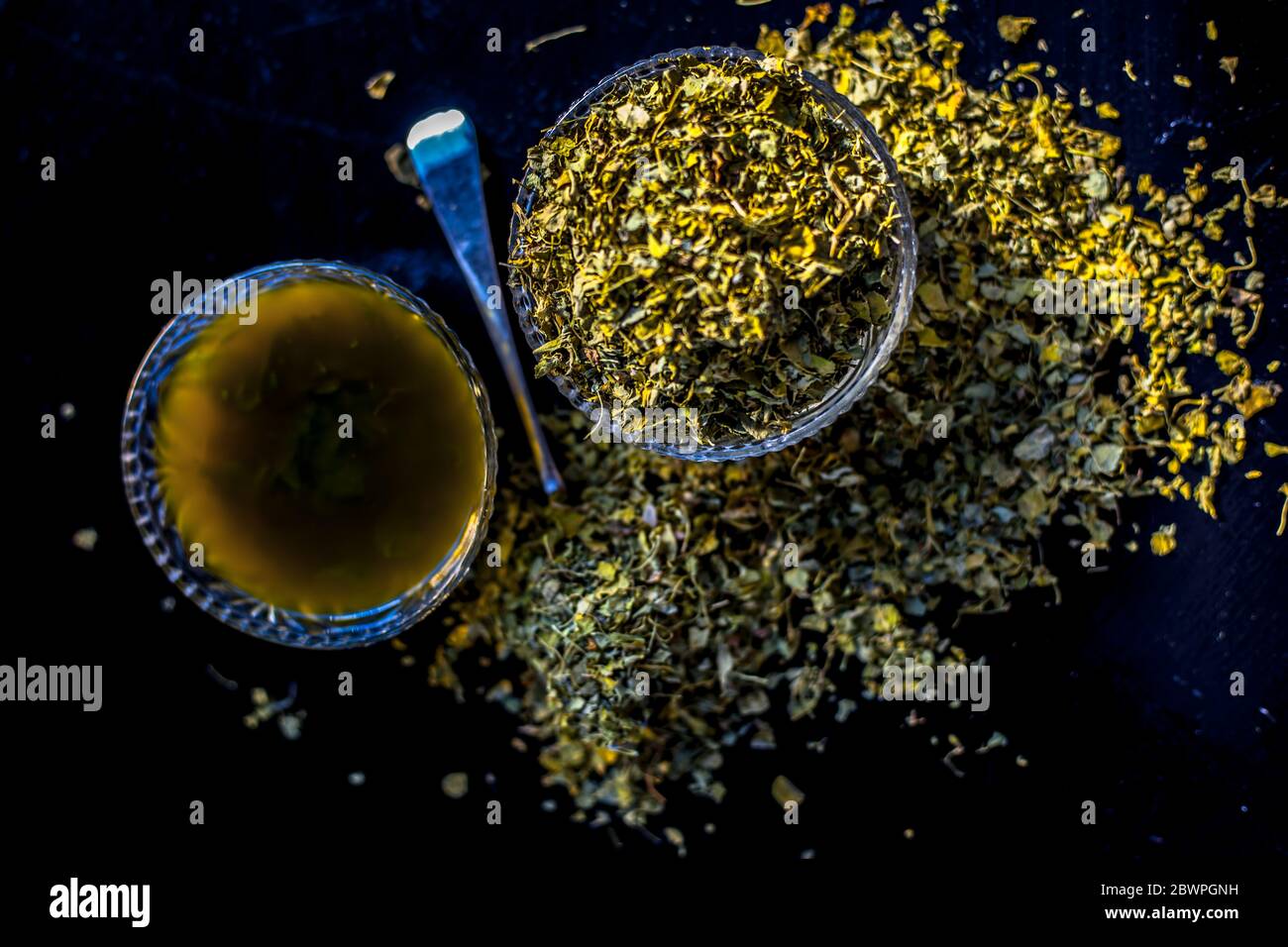 Prise de Kasuri methi cru et de sa pâte fraîchement préparée dans un bol en verre sur une surface noire brillante. Banque D'Images