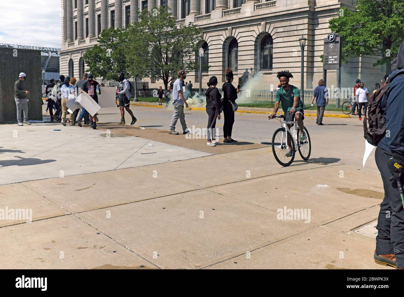 Un homme passe son vélo à travers les manifestants comme une bombe à gaz lacrymogène tirée par la police qui a frappé à proximité à Cleveland, Ohio, lors d'une manifestation de Black Lives Matter. Banque D'Images