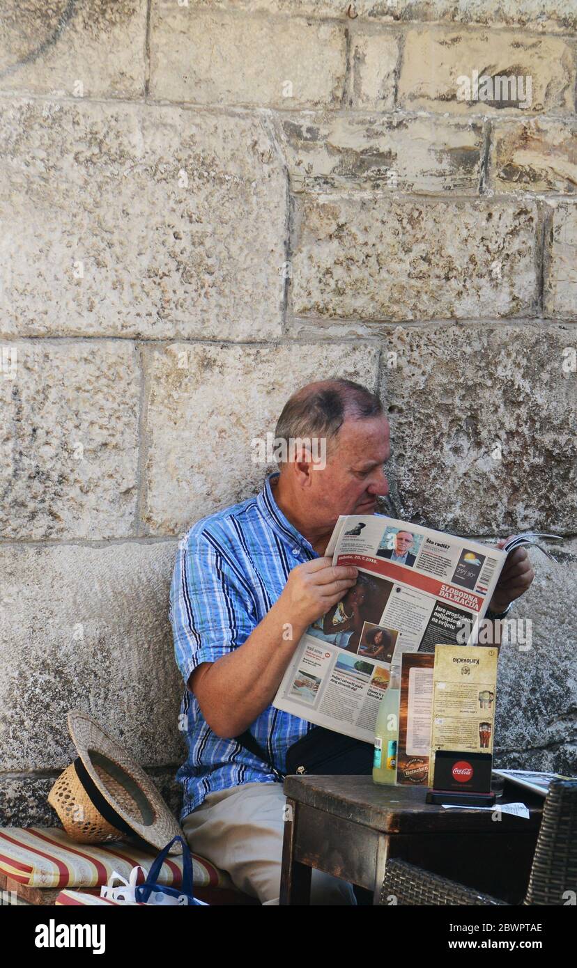 Un croate lisant le journal du matin au palais des Dioclétiens de Split, en Croatie. Banque D'Images