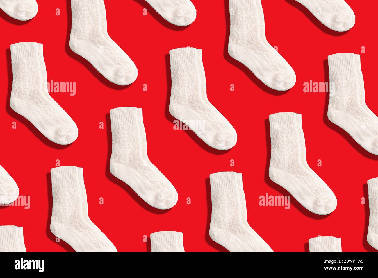 Paire de chaussettes tricotées en laine blanche sur fond rouge. Vue de dessus. Copier l'espace. Design créatif pour l'emballage. Noël et nouvel an vacances confortables Banque D'Images