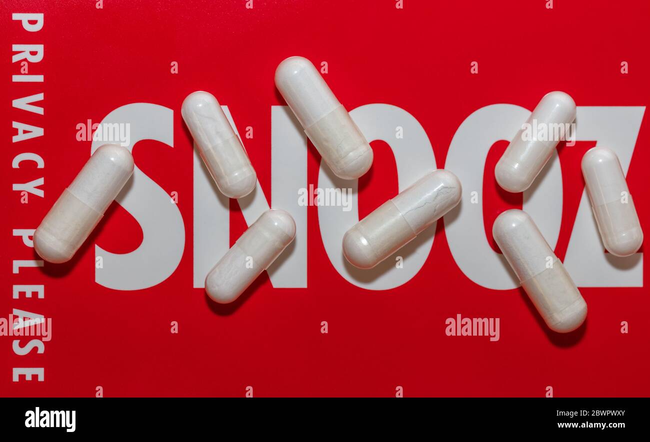 Gros plan de pilules blanches sur le panneau rouge de snoozing avec fond de mise au point douce. Contexte avec les mots « Snooz » et « Privacy Please » Banque D'Images