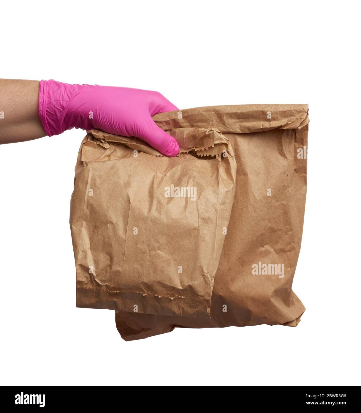 main dans un gant en latex rose contient un sac en papier complet de papier  marron, concept de livraison de nourriture à distance et sans contact,  réception sûre des commandes Photo Stock -