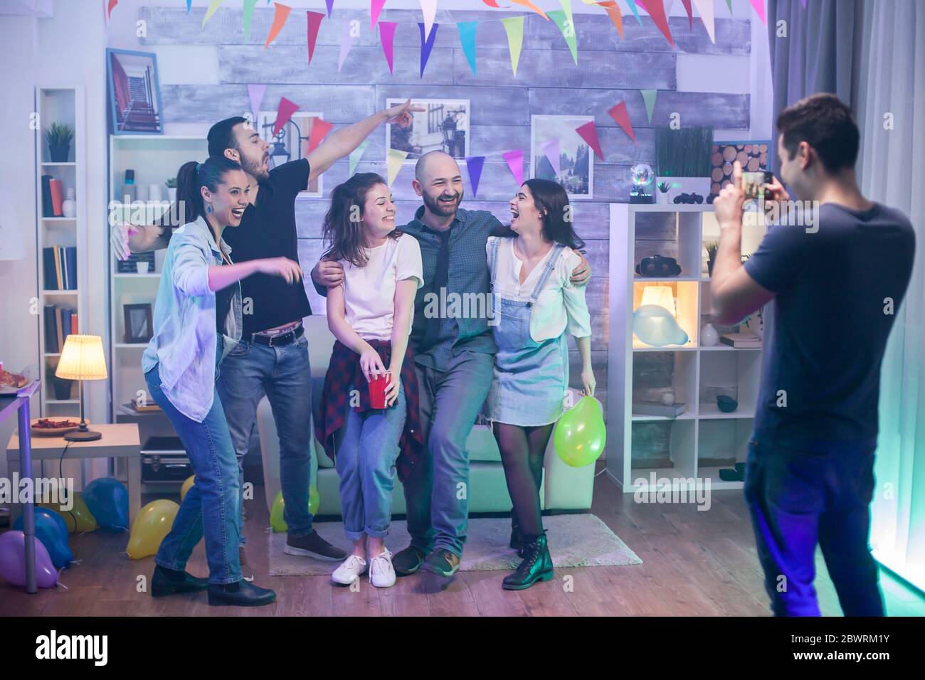 Groupe d'amis célébrant leur amitié lors d'une fête et prenant une photo de groupe. Banque D'Images