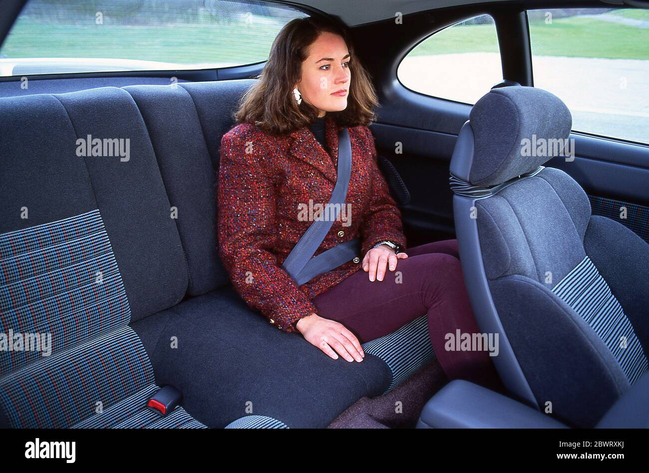 Jeune femme assise à l'arrière d'une voiture avec sa ceinture de sécurité  Photo Stock - Alamy