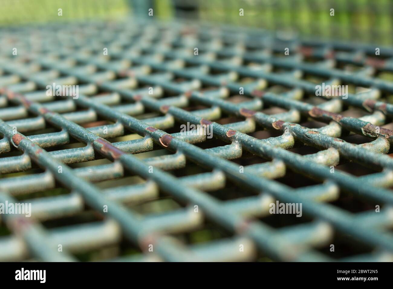 Vue inclinée d'une grille de paillasse de parc en métal vert avec décollement de la peinture, mise au point sélectionnée Banque D'Images